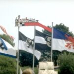 Neben der Flagge der I.G.mini-sail wehen die Fahnen Mecklenburgs, Pommerns und Ostpreussens. Darüber ein geschnitzter Kurenwimpel.