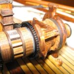 Der Hartholzklotz in der Drahtführung rastet beim Drehen der Winde in das zentrale Klinkenrad ein und nimmt die ganzen Kräfte auf, die vom Anker auf die Winde wirken. Sollte die Trommel ablaufen, so musste auch dieser Klotz hochgezogen werden.